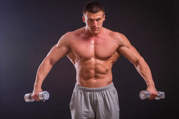 Fisiculturista posando em diferentes poses demonstrando seus músculos. Falha num fundo escuro. Homem mostrando músculos se esforçando. Bonito atleta corpo muscular . — Fotografia de Stock