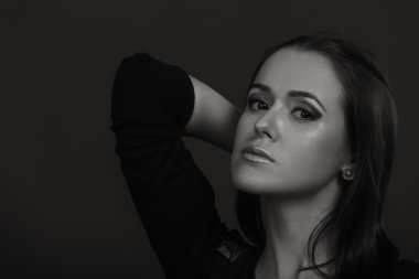 Karanlık bir arka plan üzerinde güzel, gizemli, şirin esmer. Siyah ve beyaz fotoğraf güzel gizemli esmer.