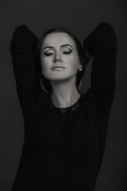 Karanlık bir arka plan üzerinde güzel, gizemli, şirin esmer. Siyah ve beyaz fotoğraf güzel gizemli esmer.