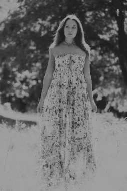 Beyaz elbiseli genç esmer kadın. Bir kız, güneşli bir günde pembe çiçekler tarlanın ortasında duruyor. Alan, çiçekler güzellik, doğa, - ülke tatil kavramı. Tatil hakkında makale.