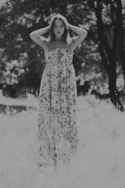 Beyaz elbiseli genç esmer kadın. Bir kız, güneşli bir günde pembe çiçekler tarlanın ortasında duruyor. Alan, çiçekler güzellik, doğa, - ülke tatil kavramı. Tatil hakkında makale.