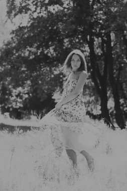 Beyaz elbiseli genç esmer kadın. Bir kız, güneşli bir günde pembe çiçekler tarlanın ortasında duruyor. Alan, çiçekler güzellik, doğa, - ülke tatil kavramı. Tatil hakkında makale.