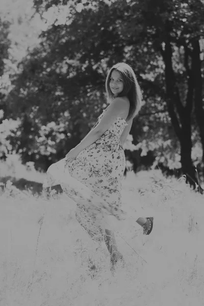 Jonge brunette vrouw in een witte jurk. Een meisje staat in het midden van de roze bloemen veld op een zonnige dag. Veld bloemen schoonheid, natuur, -het concept van land vakantie. Artikel over vakantie. — Stockfoto