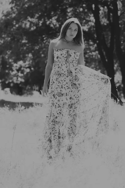 Jonge brunette vrouw in een witte jurk. Een meisje staat in het midden van de roze bloemen veld op een zonnige dag. Veld bloemen schoonheid, natuur, -het concept van land vakantie. Artikel over vakantie. — Stockfoto