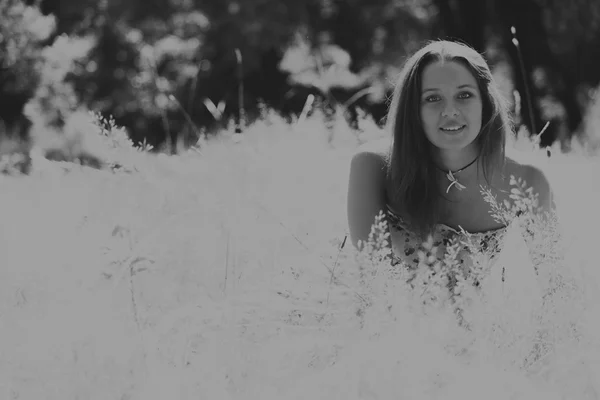 Jonge brunette vrouw in een witte jurk. Een meisje staat in het midden van de roze bloemen veld op een zonnige dag. Veld bloemen schoonheid, natuur, -het concept van land vakantie. Artikel over vakantie. — Stockfoto