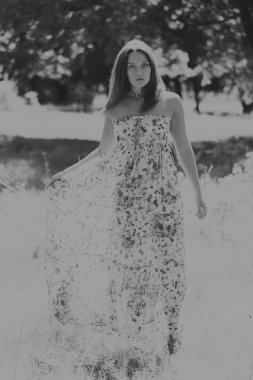 Beyaz elbiseli genç esmer kadın. Bir kız, güneşli bir günde pembe çiçekler tarlanın ortasında duruyor. Alan, çiçekler güzellik, doğa, - ülke tatil kavramı. Tatil hakkında makale.