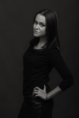 Karanlık bir arka plan üzerinde güzel, gizemli, şirin esmer. Siyah ve beyaz fotoğraf güzel gizemli esmer.