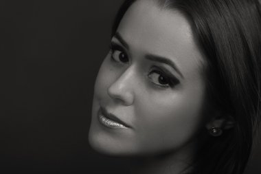 Karanlık bir arka plan üzerinde güzel, gizemli, şirin esmer. Siyah ve beyaz fotoğraf güzel gizemli esmer.
