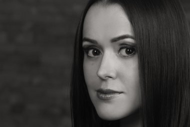 Karanlık bir arka plan üzerinde güzel, gizemli, şirin esmer. Siyah ve beyaz fotoğraf güzel gizemli esmer.