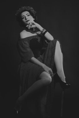 Karanlık bir arka plan üzerinde güzel, gizemli, şirin esmer. Siyah ve beyaz fotoğraf güzel gizemli esmer.