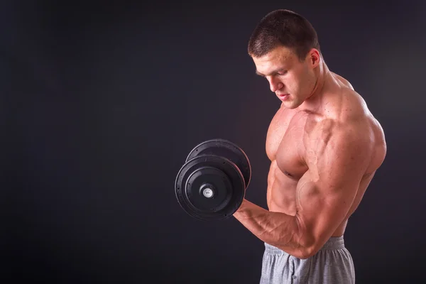 Bodybuilder posant dans différentes poses démontrant leurs muscles. Échec sur fond sombre. Homme montrant des muscles tendus. Magnifique athlète du corps musculaire . — Photo