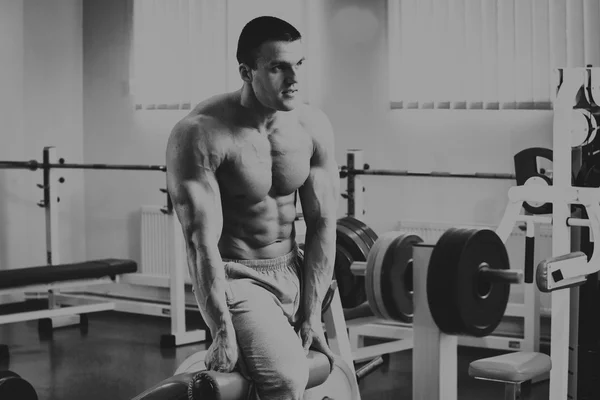 Muskelprotz in der Turnhalle. Arbeit an der Armmuskulatur. Training am Simulator. Anstrengende Arbeit an seinem Körper. — Stockfoto