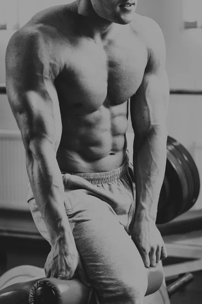 Hombre musculoso en el gimnasio. Trabaja en los músculos del brazo. Entrenamiento en un simulador. Trabajo agotador en su cuerpo . — Foto de Stock