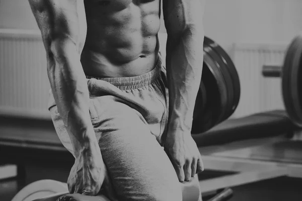 Gespierde man in de sportschool. Werken op de armspieren. Training op een simulator. Vermoeiend werk op zijn lichaam. — Stockfoto