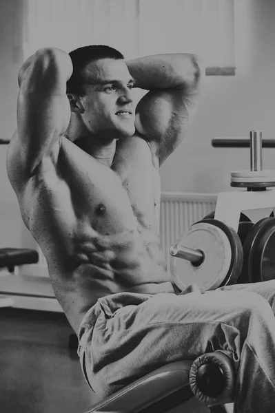 М'язистий чоловік у спортзалі. Робота над м'язами рук. Тренування на симуляторі. Виснажлива робота над його тілом . — стокове фото