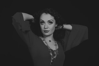 Karanlık bir arka plan üzerinde güzel, gizemli, şirin esmer. Siyah ve beyaz fotoğraf güzel gizemli esmer.