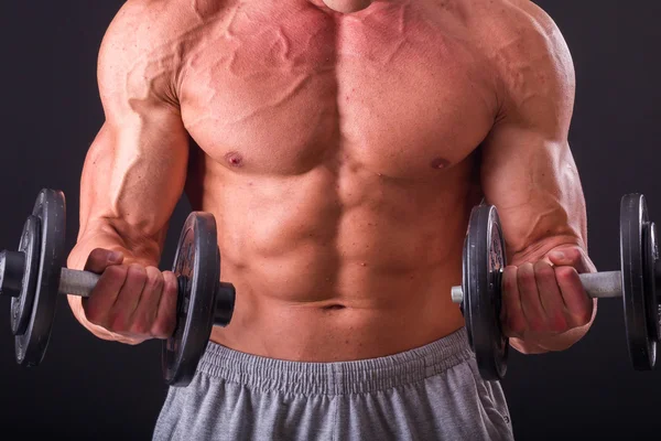 Fisiculturista posando em diferentes poses demonstrando seus músculos. Falha num fundo escuro. Homem mostrando músculos se esforçando. Bonito atleta corpo muscular . — Fotografia de Stock