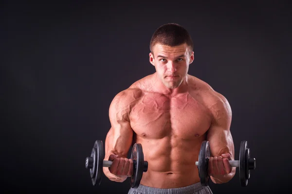 Bodybuilder posing in different poses demonstrating their muscles. Failure on a dark background. Male showing muscles straining. Beautiful muscular body athlete. Stock Picture