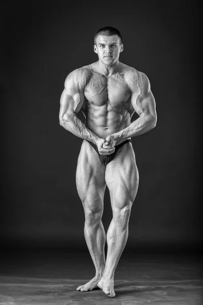 Bodybuilder posing on a black background, black and white photo — Stock Photo, Image