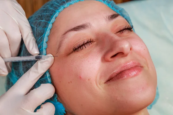 Inyección cosmética en el salón de spa. El esteticista inyecta en la cara del paciente . — Foto de Stock