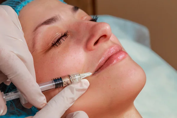 Inyección cosmética en el salón de spa. El esteticista inyecta en la cara del paciente . — Foto de Stock