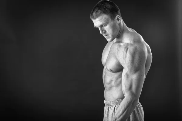 Bodybuilder posing in different poses demonstrating their muscles. Failure on a dark background. Male showing muscles straining. Beautiful muscular body athlete. — Stock Photo, Image