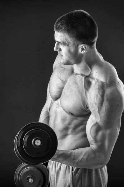 Bodybuilder poseren in verschillende poses aan te tonen hun spieren. Storing op een donkere achtergrond. Mannelijke weergegeven: spieren spannen. Mooi gespierd lichaam atleet. — Stockfoto