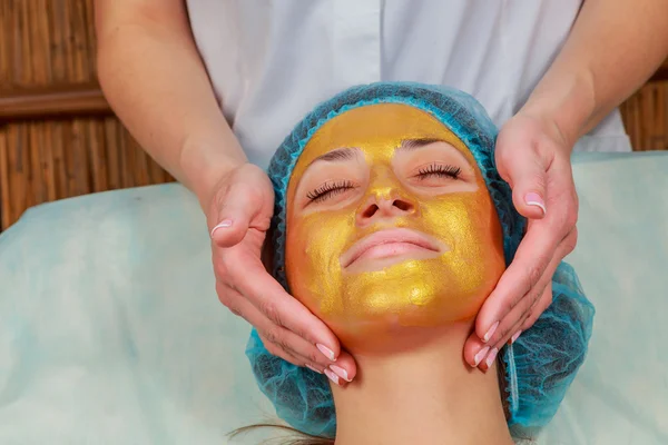 Toepassing van gouden maskers op het gezicht van het model. Cosmetische ingrepen — Stockfoto