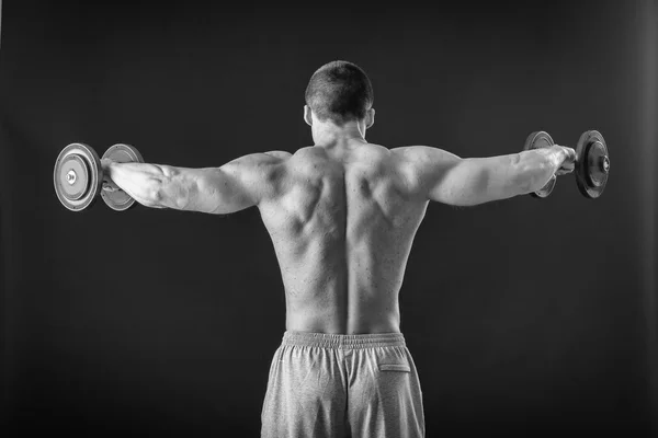 Kulturista pózuje v různých pózách, prokazující jejich svaly. Neúspěch na tmavém pozadí. Mužské zobrazeno svaly napínat. Krásné svalnaté tělo sportovce. — Stock fotografie