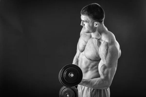 Culturista posando en diferentes poses demostrando sus músculos. Fracaso en un fondo oscuro. Varón mostrando tensión muscular. Hermoso atleta cuerpo muscular . — Foto de Stock