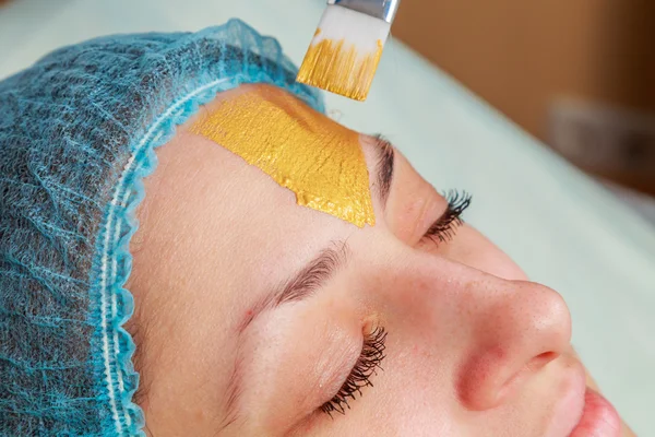 Toepassing van gouden maskers op het gezicht van het model. Cosmetische ingrepen — Stockfoto