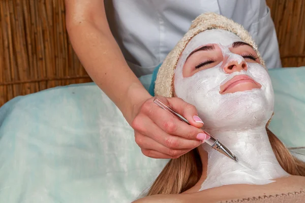 Aplicando la máscara a la cara de una joven. Piel facial en el salón de spa — Foto de Stock