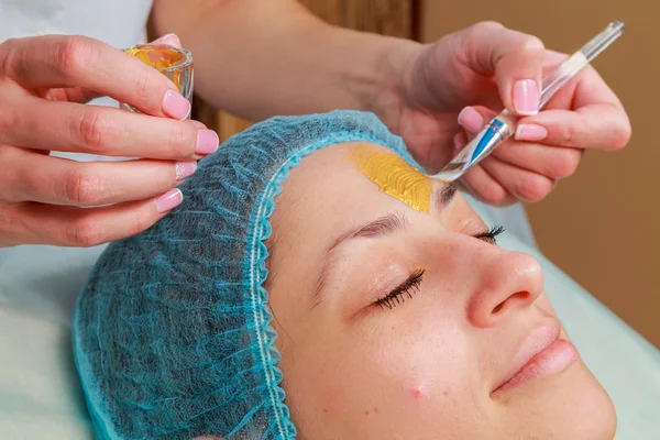 Toepassing van gouden maskers op het gezicht van het model. Cosmetische ingrepen — Stockfoto