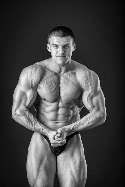 Fisiculturista posando em diferentes poses demonstrando seus músculos. Falha num fundo escuro. Homem mostrando músculos se esforçando. Bonito atleta corpo muscular . — Fotografia de Stock