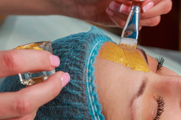 Toepassing van gouden maskers op het gezicht van het model. Cosmetische ingrepen — Stockfoto