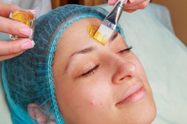 Yüzünde model altın maskesi uygulama. Kozmetik prosedürler