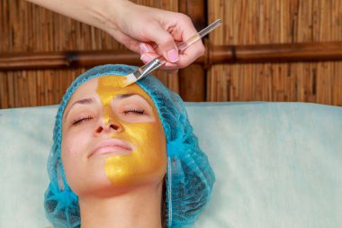 Yüzünde model altın maskesi uygulama. Kozmetik prosedürler