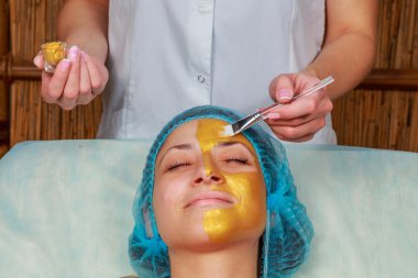 Yüzünde model altın maskesi uygulama. Kozmetik prosedürler