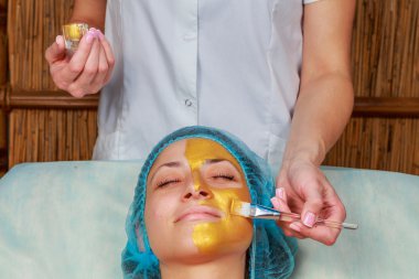 Yüzünde model altın maskesi uygulama. Kozmetik prosedürler