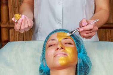 Yüzünde model altın maskesi uygulama. Kozmetik prosedürler