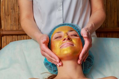 Yüzünde model altın maskesi uygulama. Kozmetik prosedürler