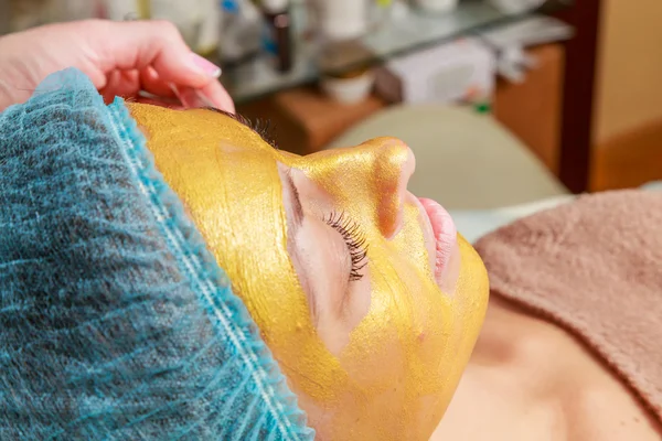 Auftragen goldener Masken auf dem Gesicht des Modells. Kosmetische Eingriffe — Stockfoto