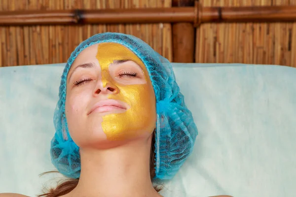 Application de masques dorés sur le visage du modèle. Procédures cosmétiques — Photo