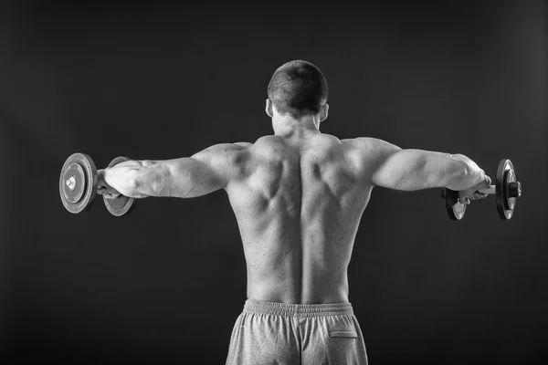 Culturista posa in pose diverse dimostrando i loro muscoli. Fallimento su uno sfondo scuro. Maschio che mostra tensione muscolare. Bellissimo atleta del corpo muscolare . — Foto Stock