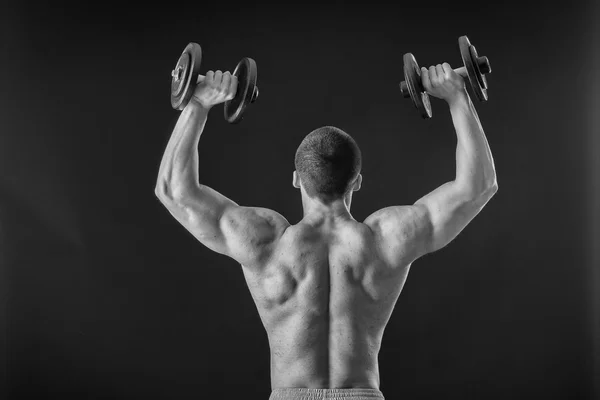 Bodybuilder posant dans différentes poses démontrant leurs muscles. Échec sur fond sombre. Homme montrant des muscles tendus. Magnifique athlète du corps musculaire . — Photo