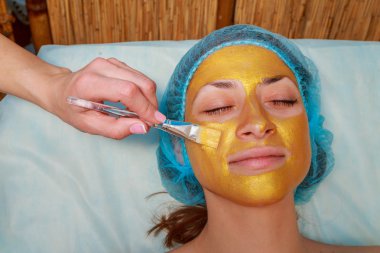 Yüzünde model altın maskesi uygulama. Kozmetik prosedürler
