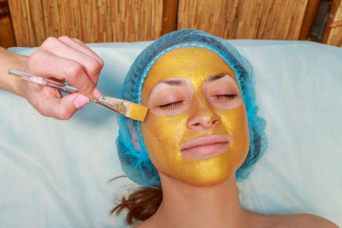 Yüzünde model altın maskesi uygulama. Kozmetik prosedürler