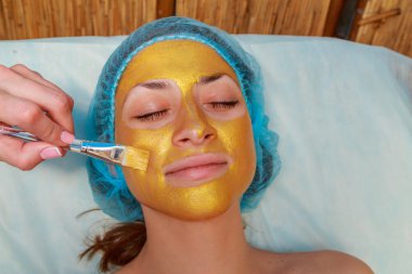 Yüzünde model altın maskesi uygulama. Kozmetik prosedürler