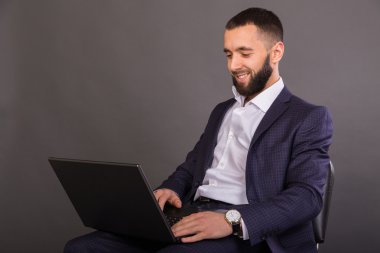 İş elbiseli genç, başarılı adam elinde bir dizüstü bilgisayar ile
