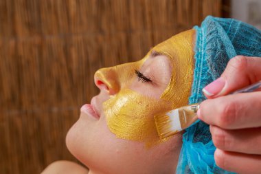 Yüzünde model altın maskesi uygulama. Kozmetik prosedürler